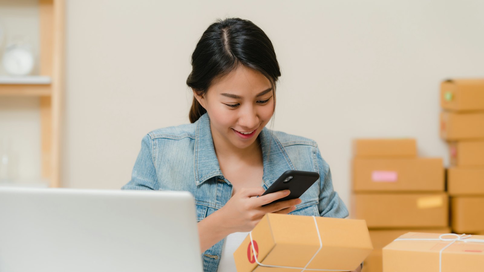 Commerçante en ligne qui prépare ses colis à côté de son ordinateur portable